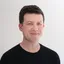 Portrait photo of designer Greg Gunn wearing a black shirt looking at camera.