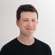 Portrait photo of designer Greg Gunn wearing a black shirt looking at camera.